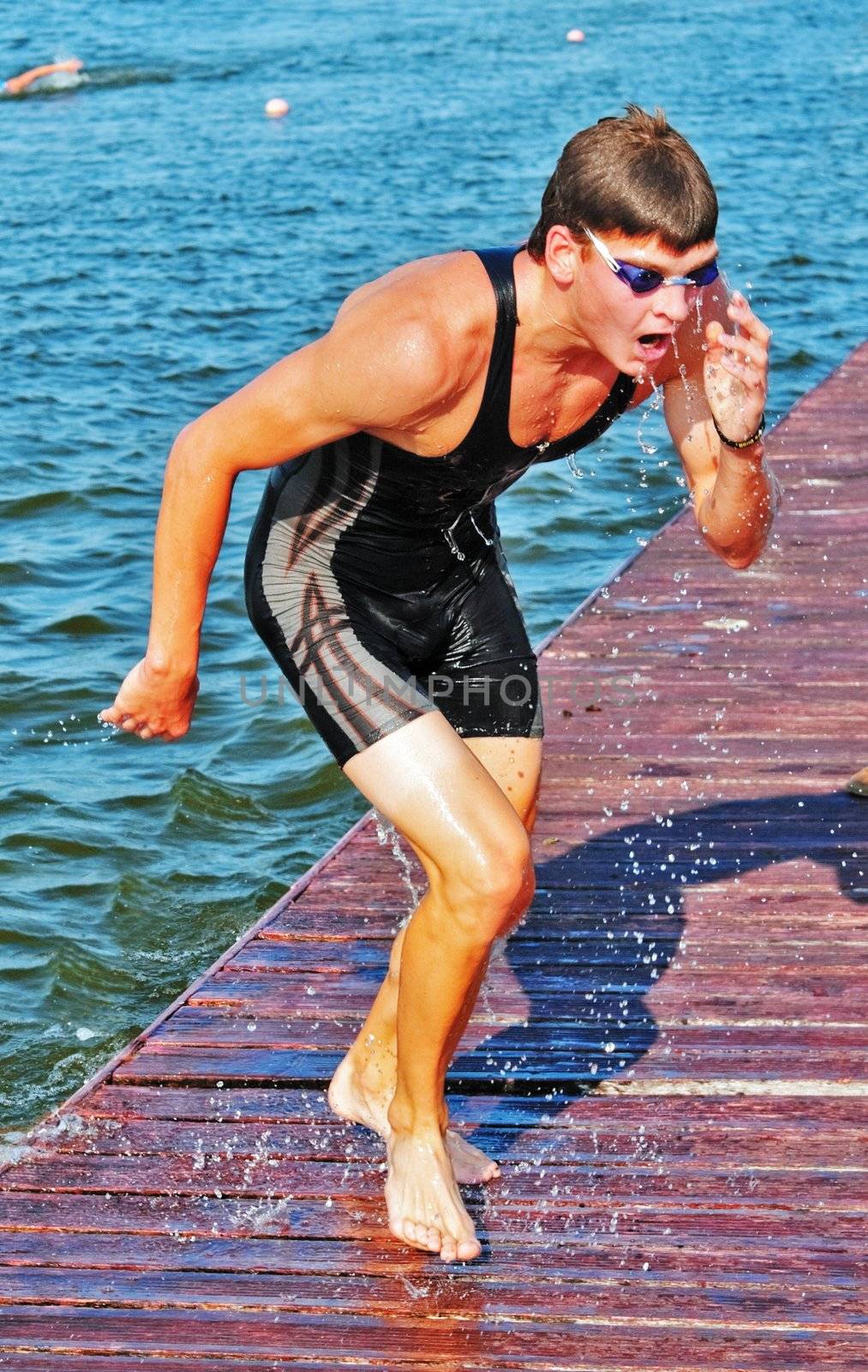 The sportsman has jumped out of water and runs on a wooden flooring of a pontoon
