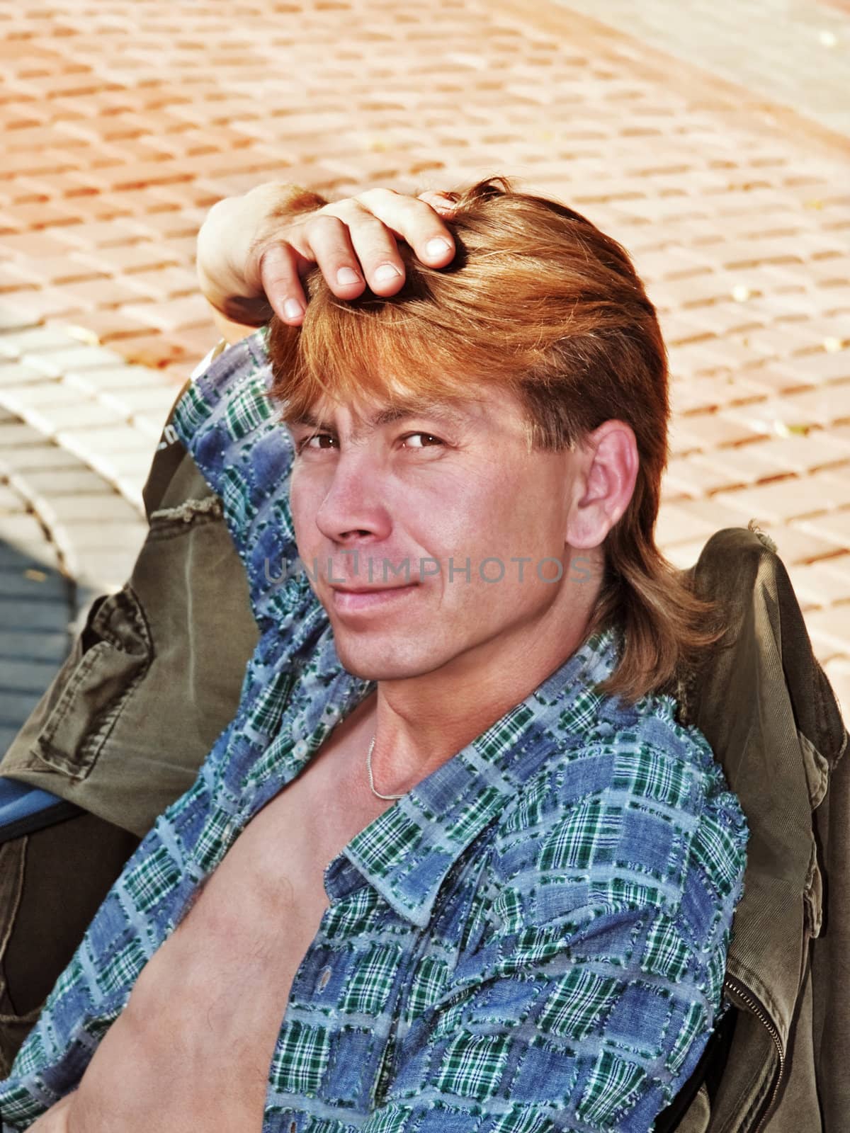 Portrait of the young man sitting on a chair in city street