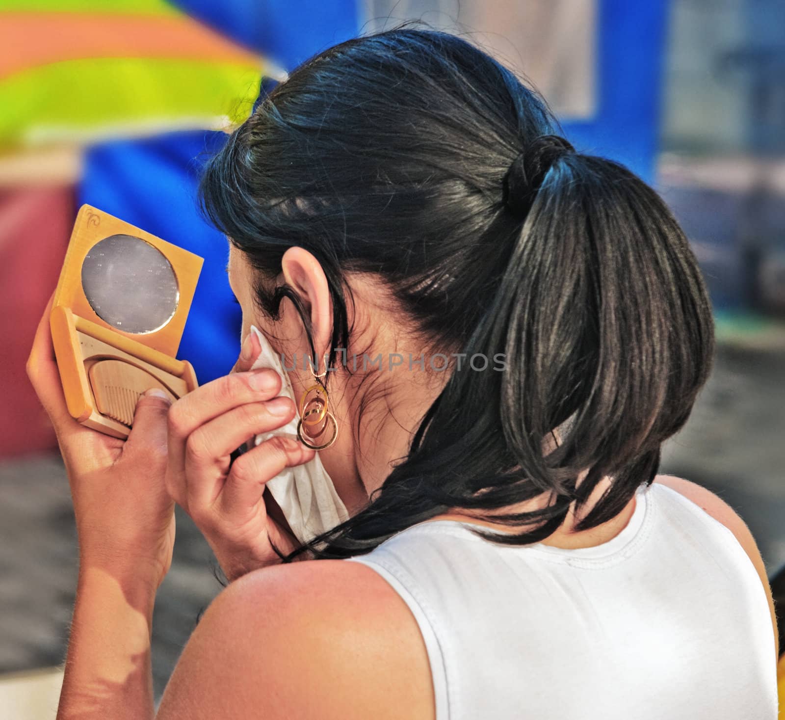 The girl looks in a pocket mirror and does a make-up