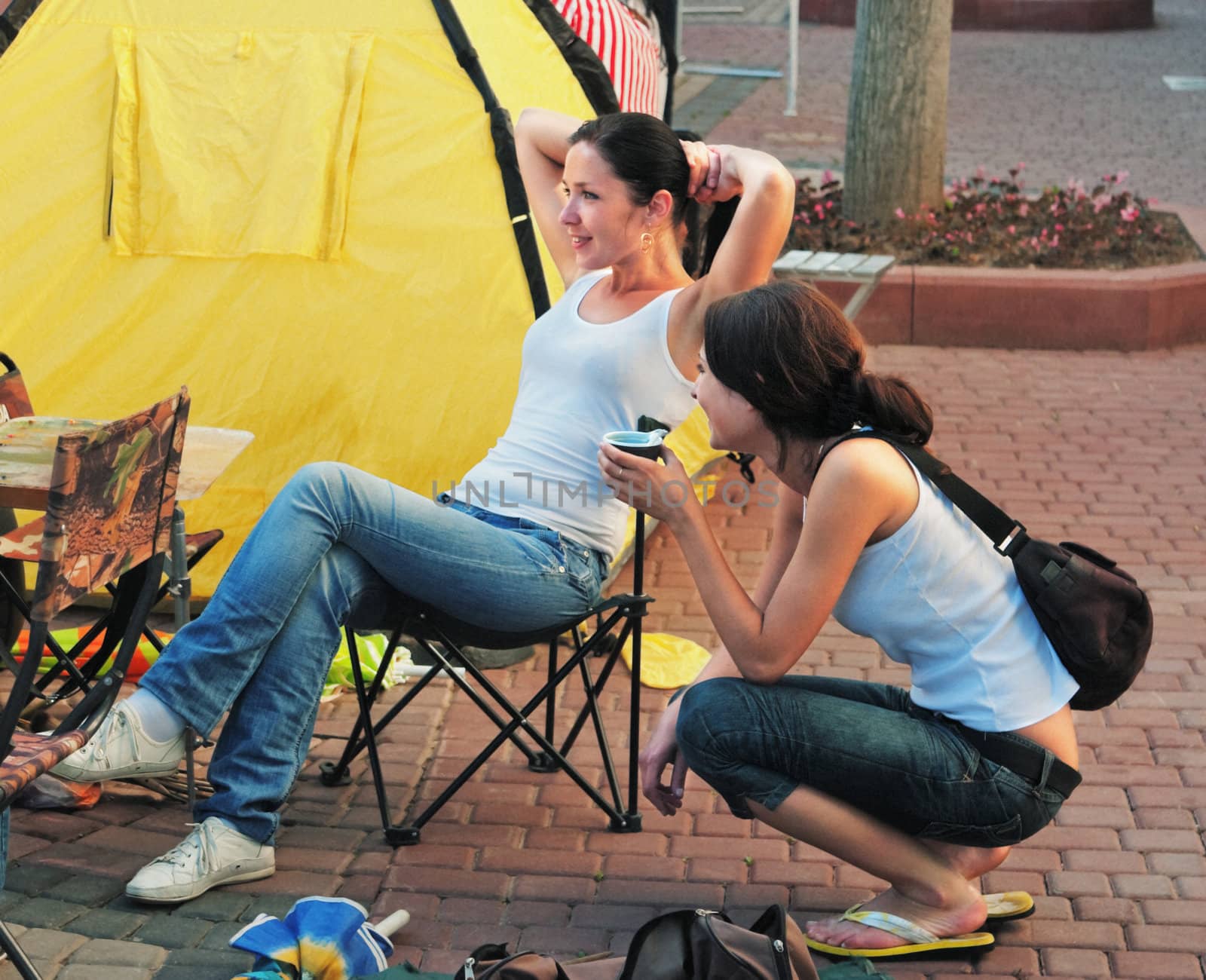The girls-artists drinks coffee from a cup in a sity street