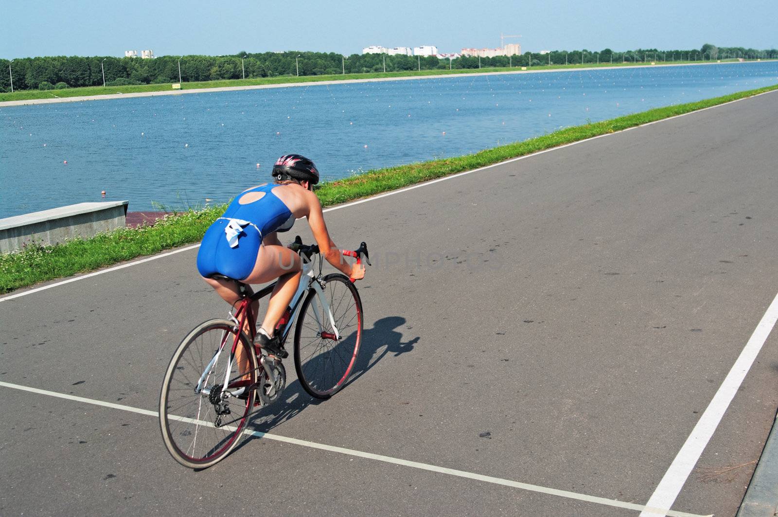 The young sportswoman goes on a bicycle on a racing line