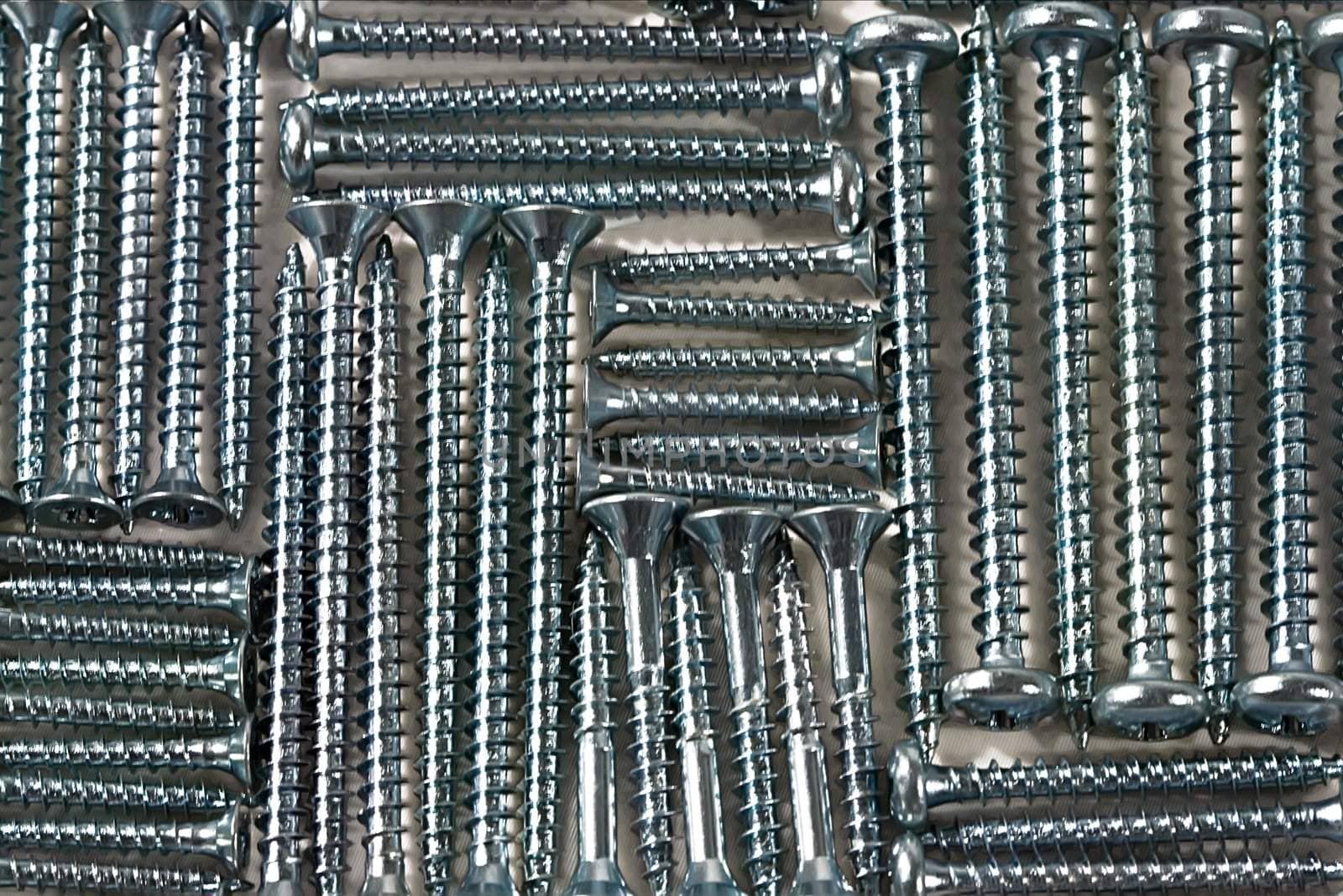 Picture made of screws different sizes on a white textile, metal and cloth, style background

