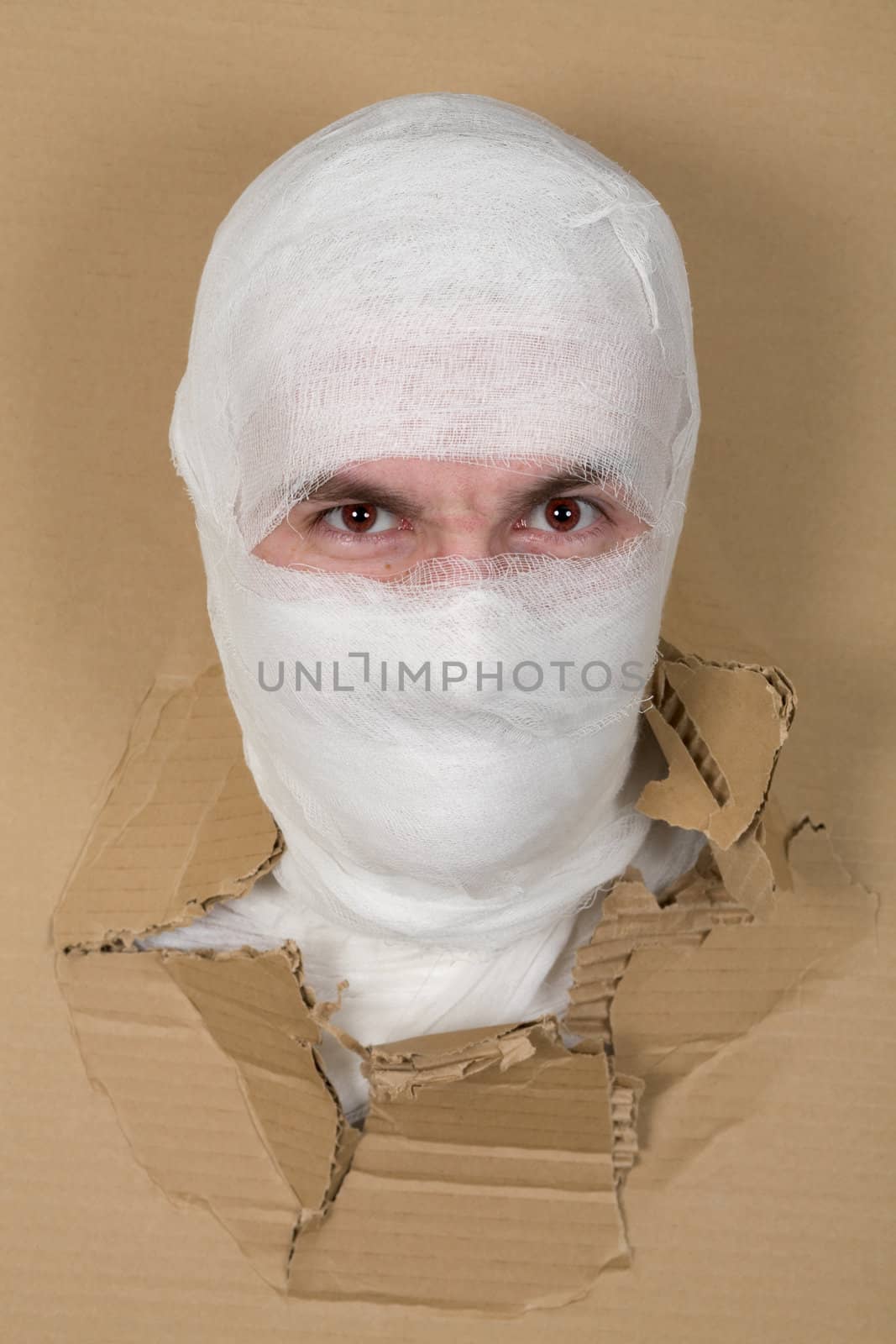 Mummy with angry face braking through the hole in cardboard