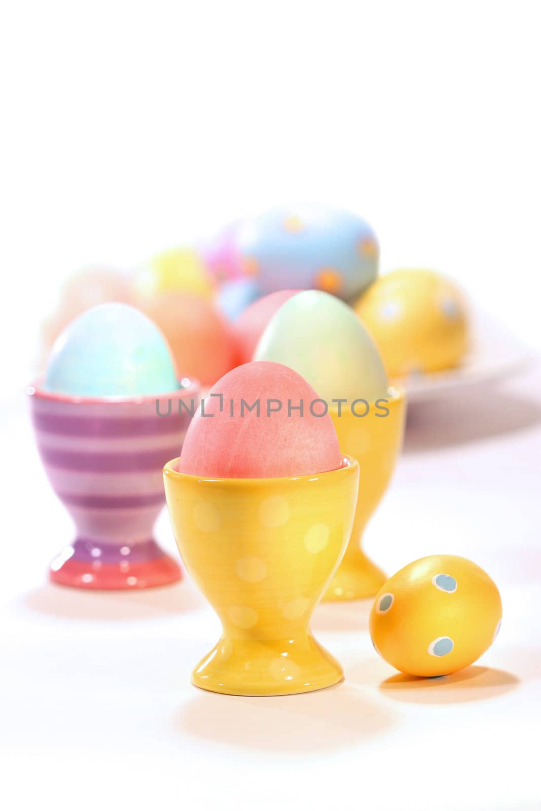 Egg cups with colored eggs on white background