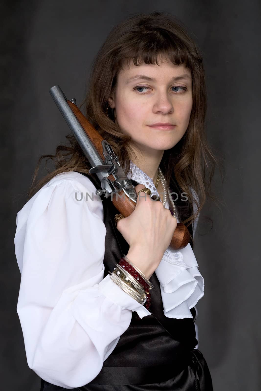 The sad girl - pirate with ancient pistol in hand on a black background