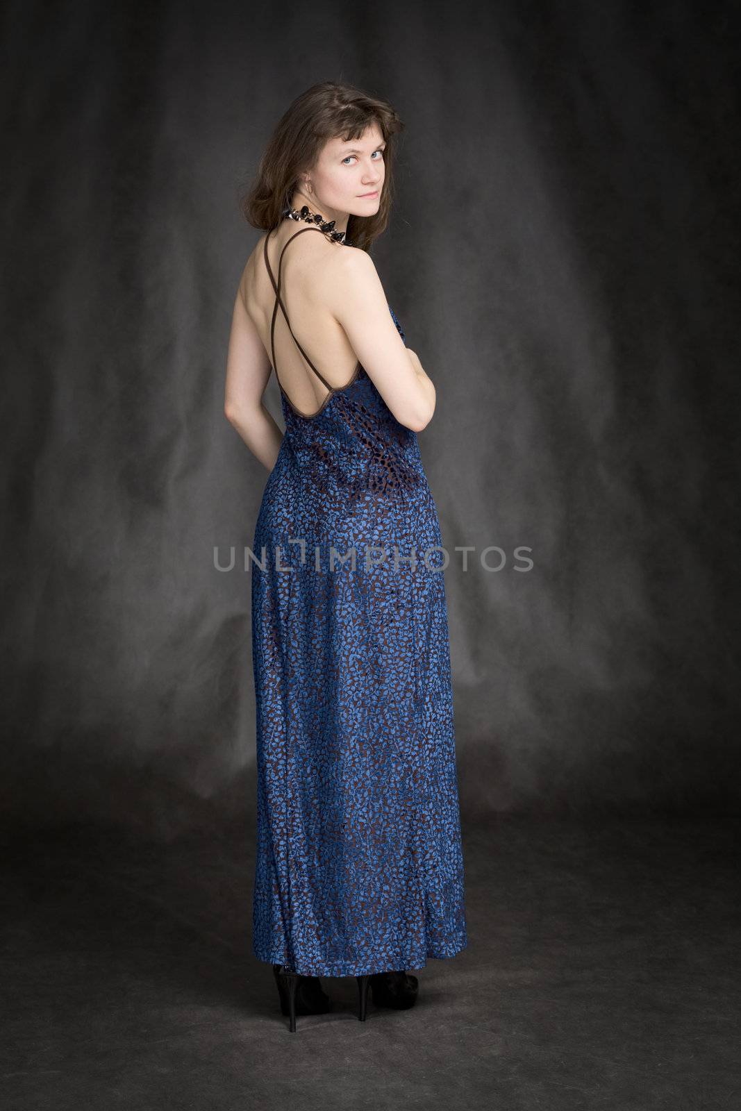 The girl in a dark blue evening dress on a black background