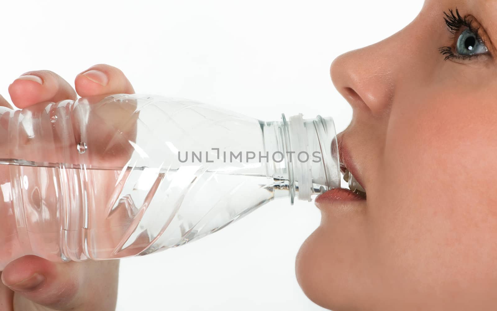 Beautiful girl drinking mineral water directly from the bottle, isolated on white background