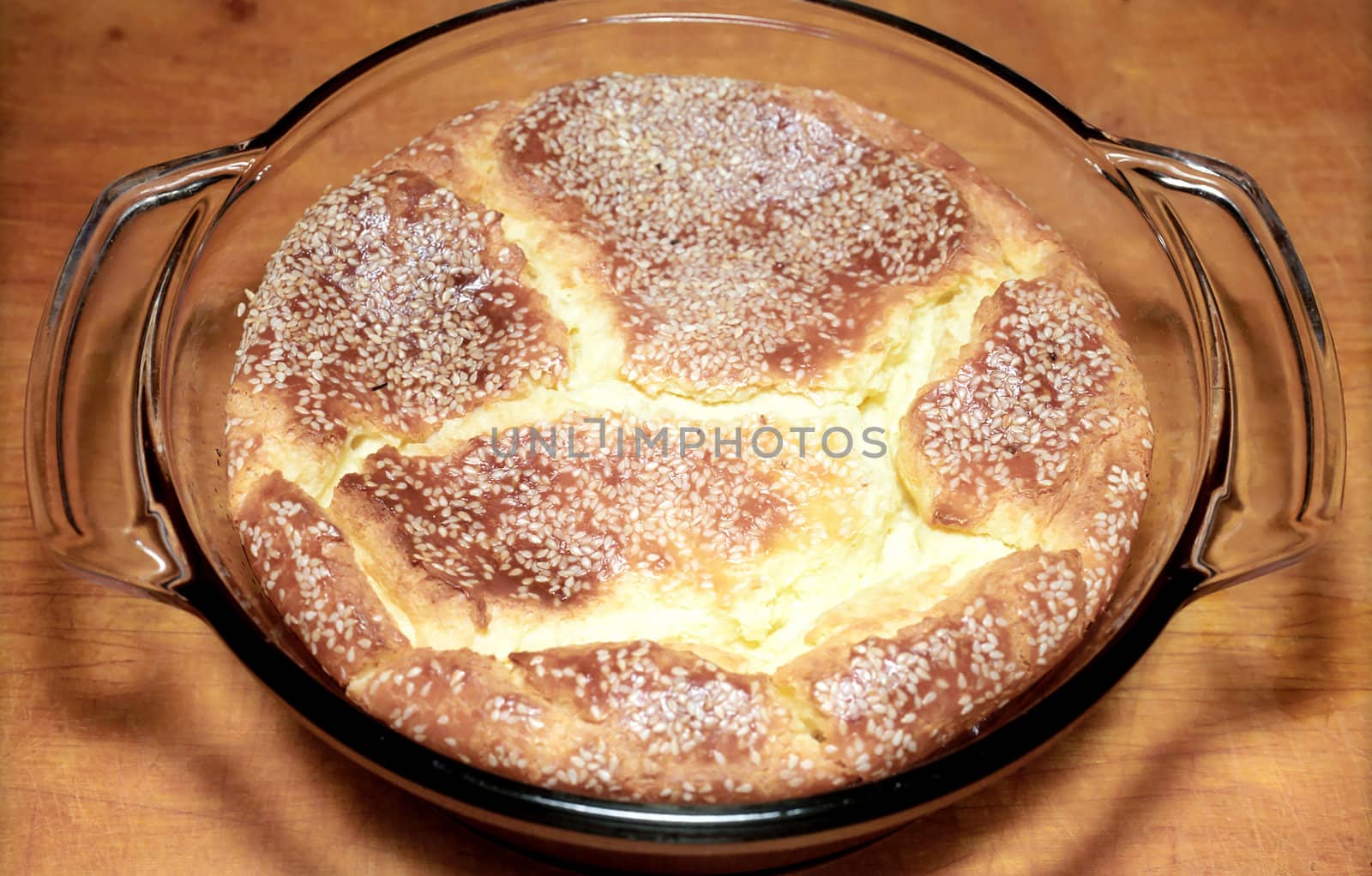 Cheese pie with sesame seeds in glass baking dish on wooden surface
