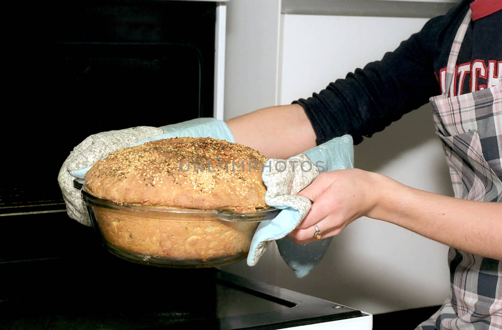 Baker woman is taking out potato bread from oven 