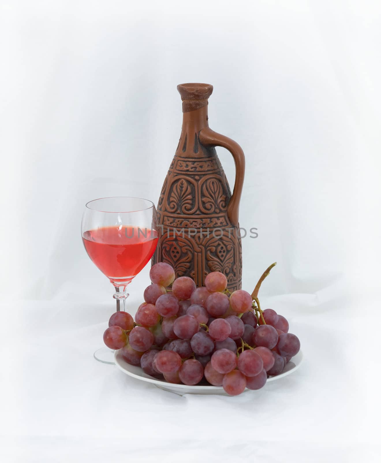 Bright still life with grapes and wine on white