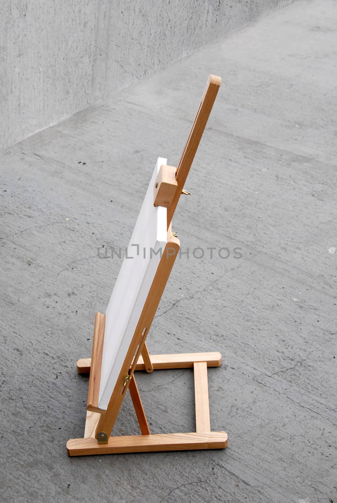 Easel with blank canvas on gray concrete background