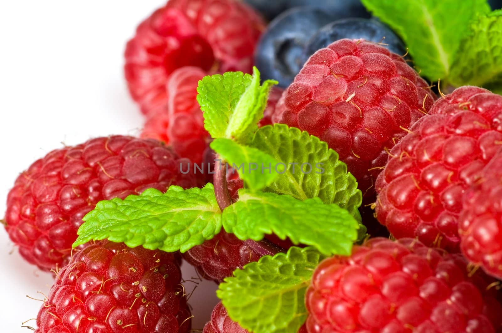 Fresh ripe raspberry and blueberry with green mint leaves 