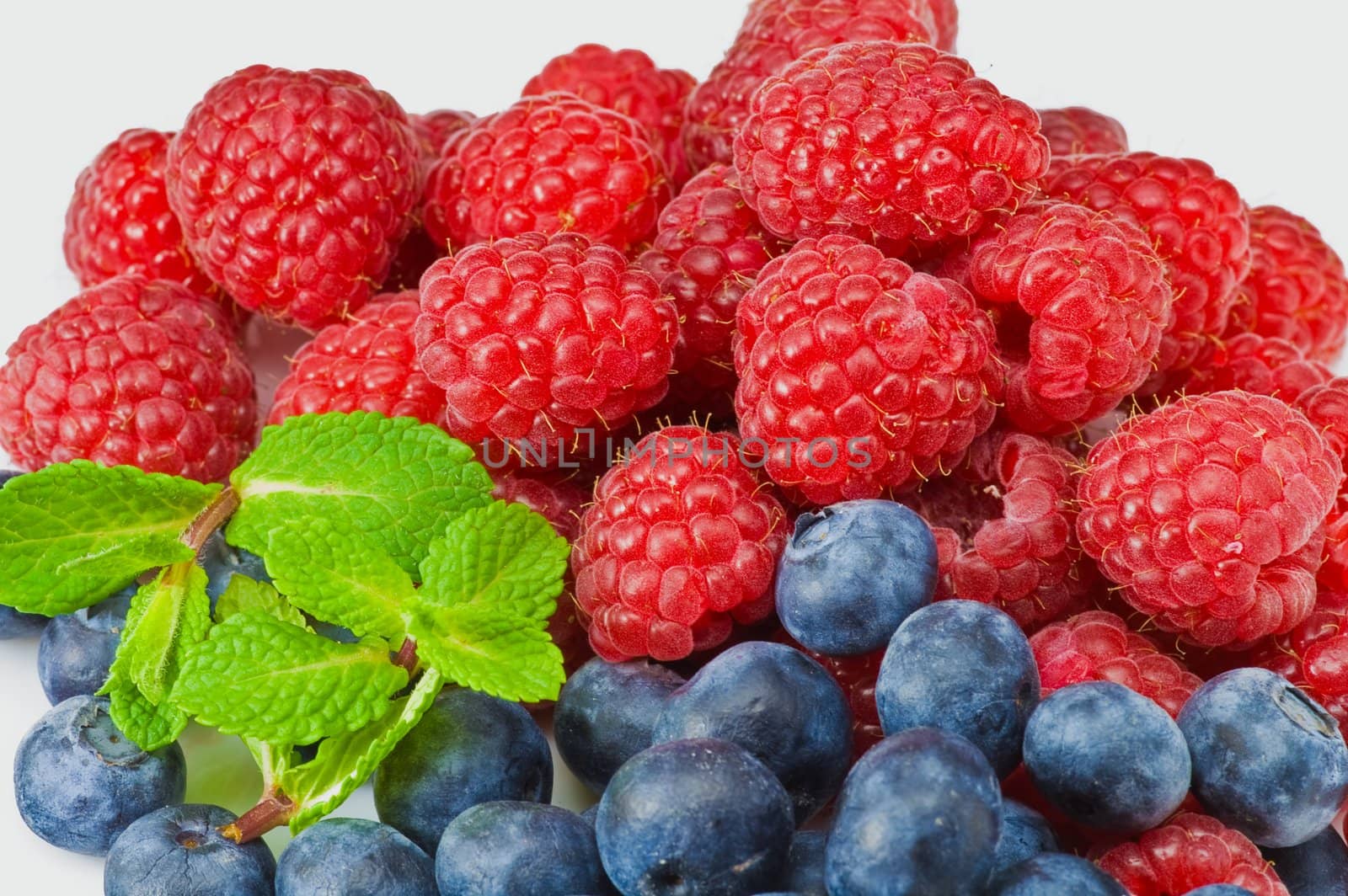 Fresh ripe raspberry and blueberry with green mint leaves 