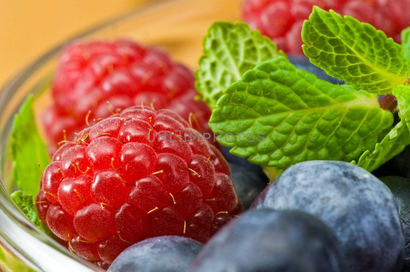 Fresh ripe raspberry and bluberry in glass jam-dish