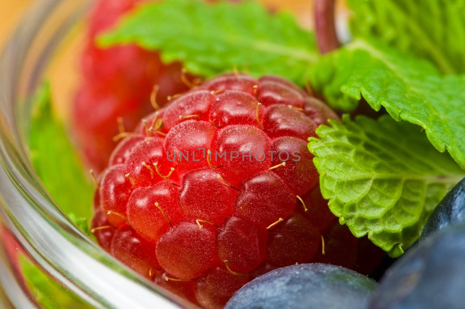 Fresh ripe raspberry and bluberry in glass jam-dish
