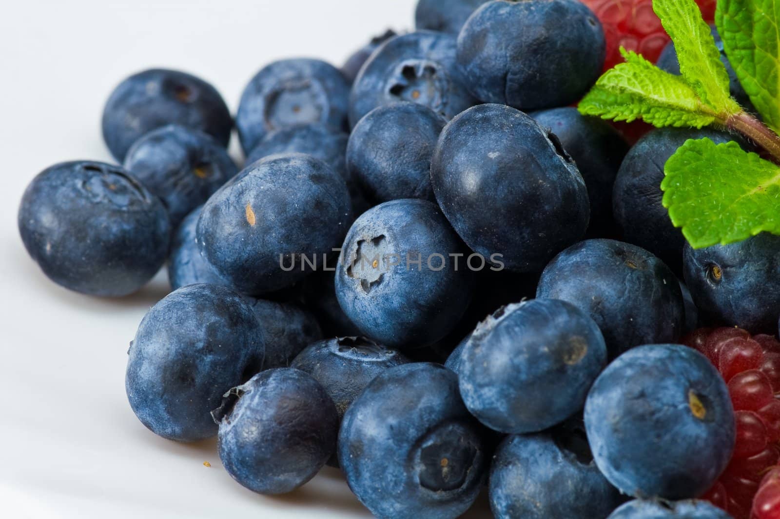 Fresh ripe raspberry and blueberry with green mint leaves 