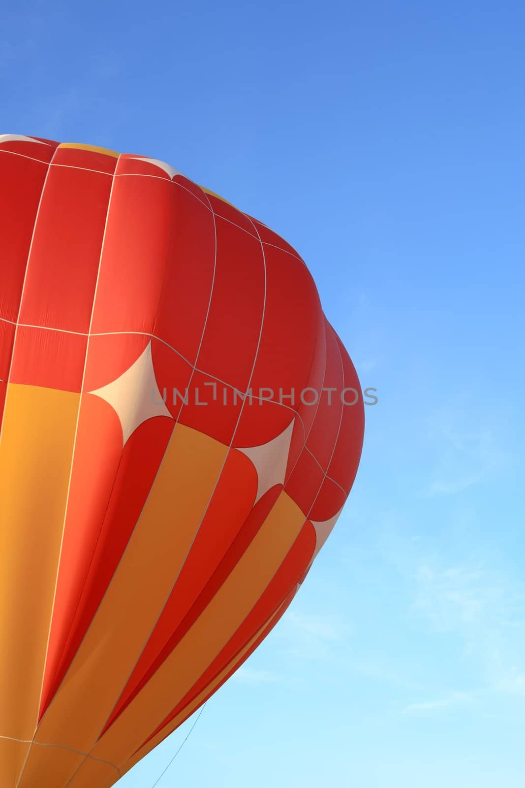 Vivid orange hot air balloon in the blue sky.