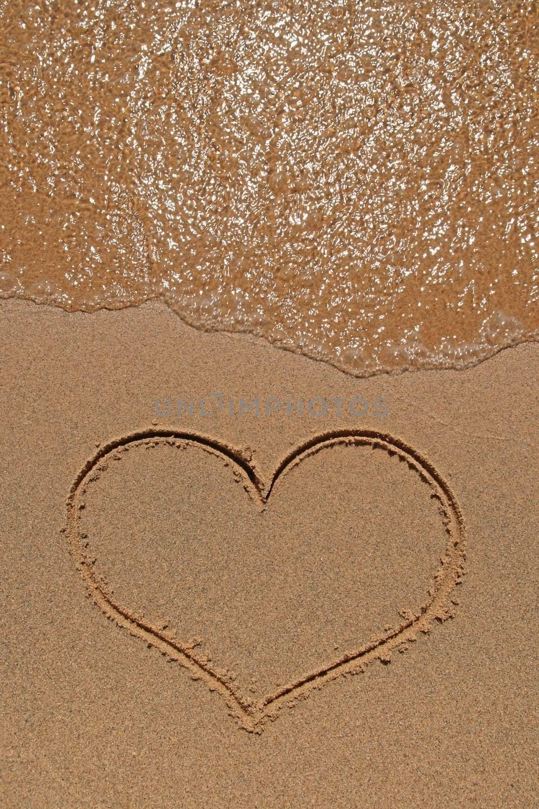 Wave running over the sand beach with heart drawing.