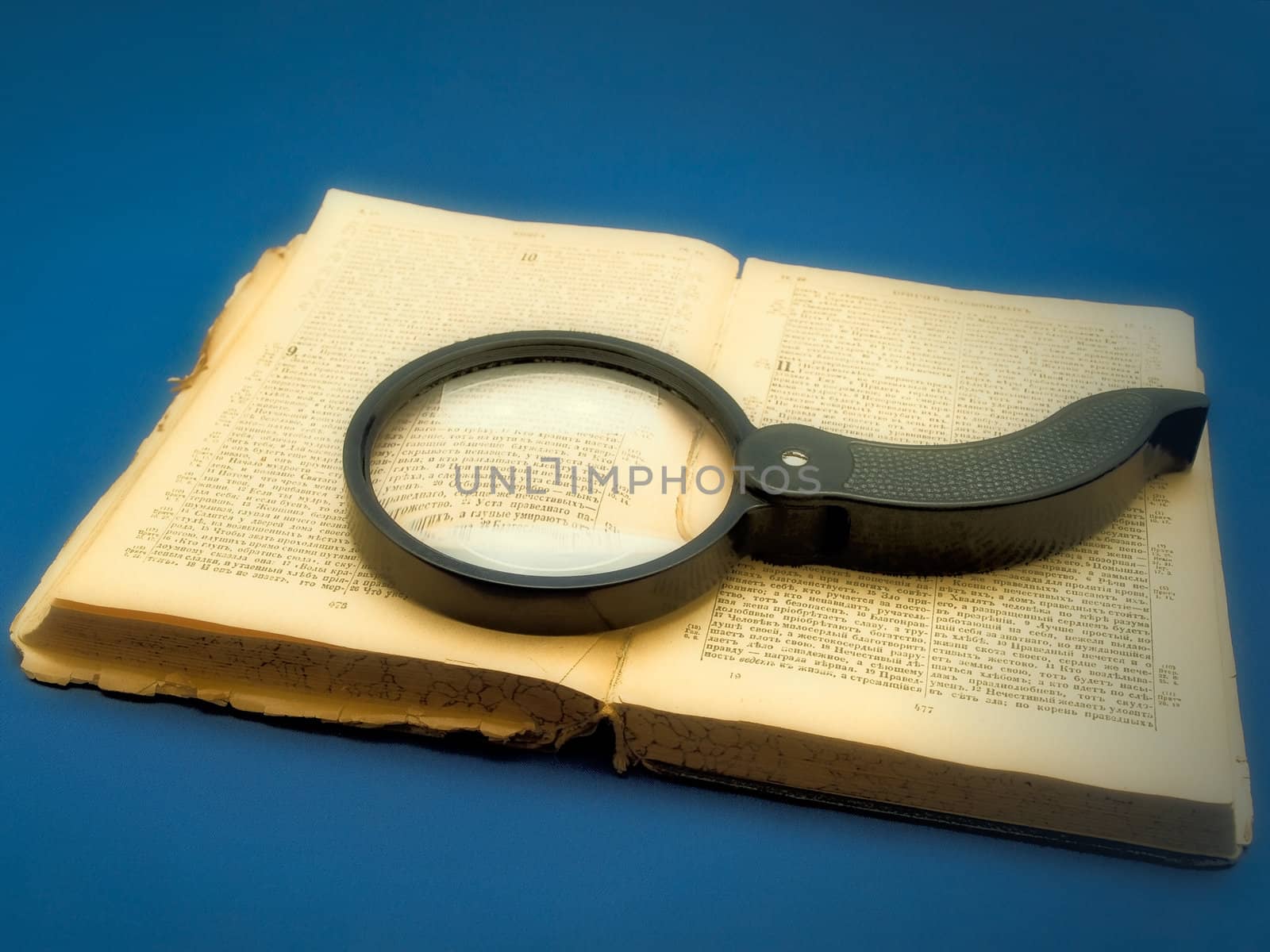 magnifier at the book with blur effect over blue background