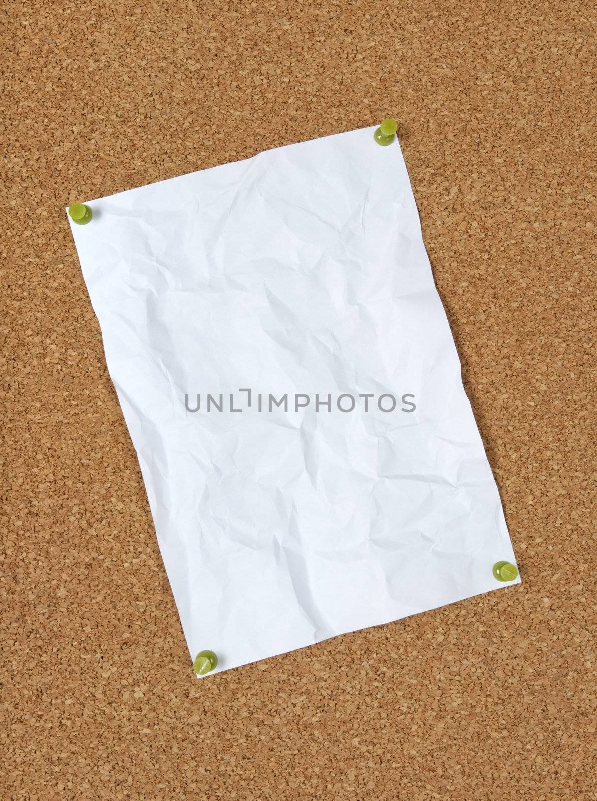 Blank crumpled paper pinned to corkboard with green pins.