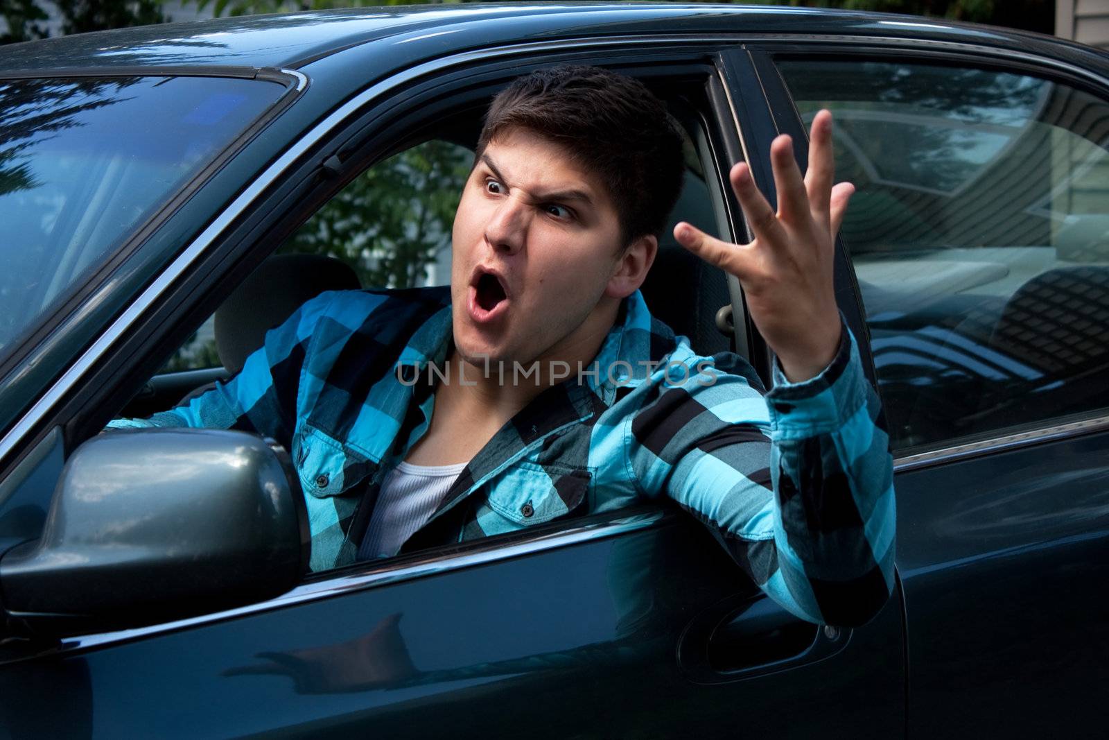 An irritated young man driving a vehicle is expressing his road rage.