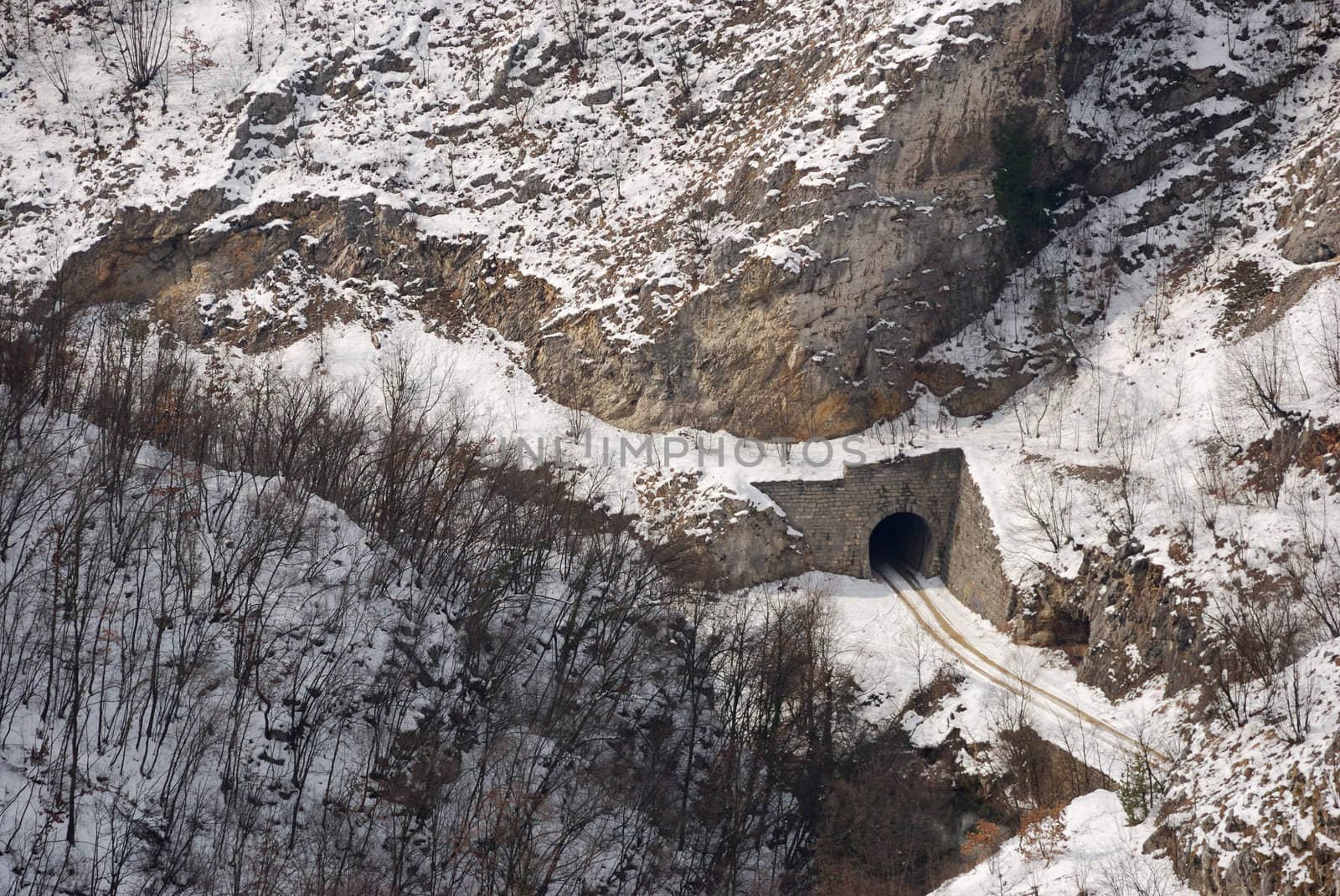 Tunnel in a hill and car trails in snow.