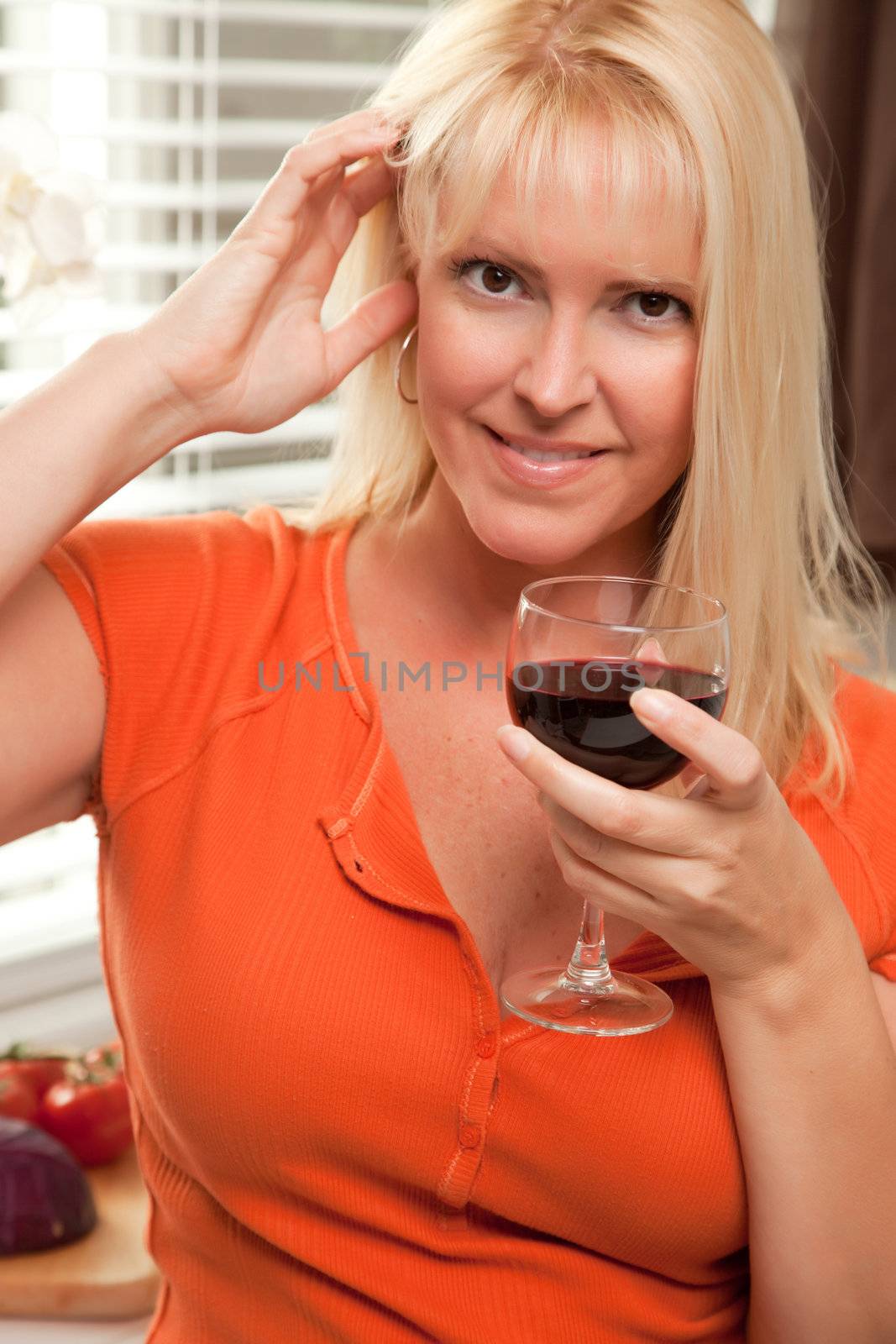 Attractive Blond with a Glass of Wine in the Kitchen