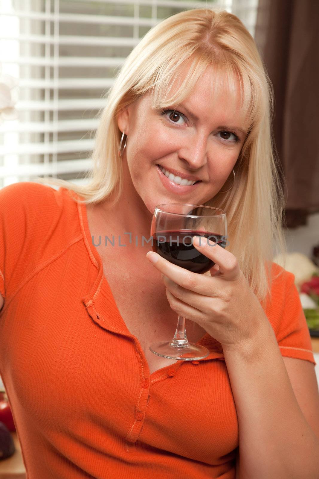 Attractive Blond with a Glass of Wine in the Kitchen