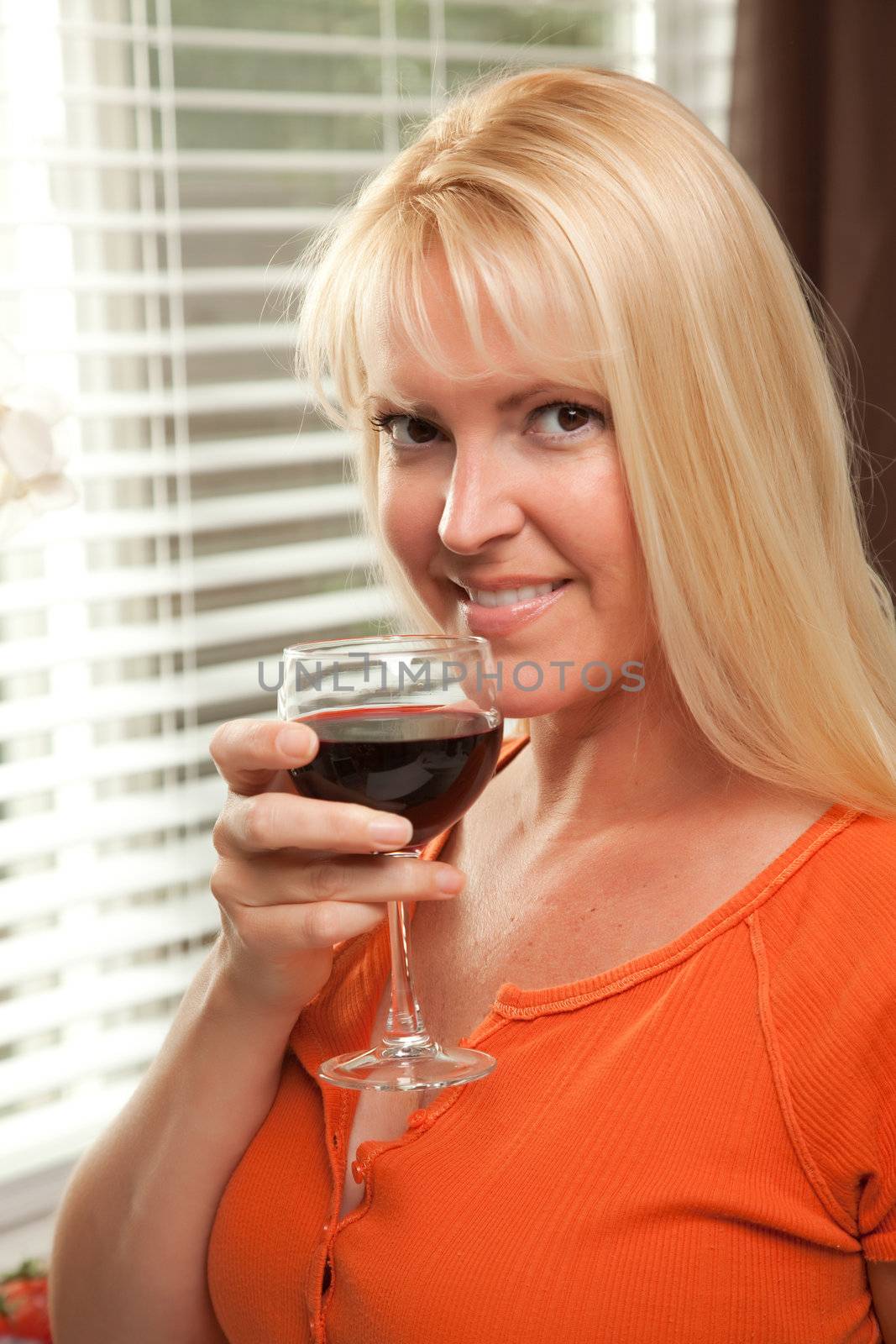 Attractive Blond with a Glass of Wine in the Kitchen