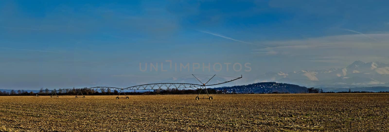 HDR Paronamic view of a corn field in winter with irrigation system and the Pyrenees mountains on the background