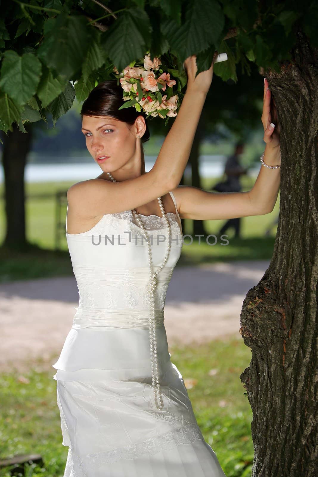Prettty bride posing under tree.
