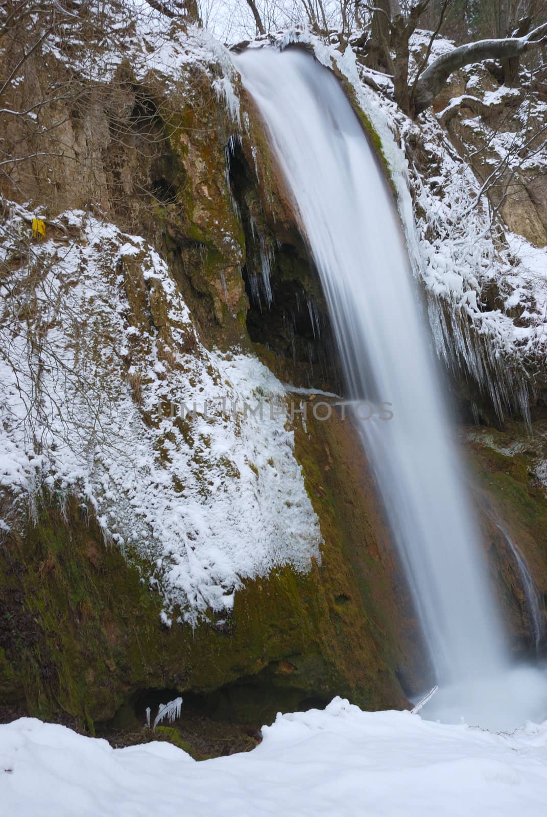 Waterfall surrounded with snow and icicles