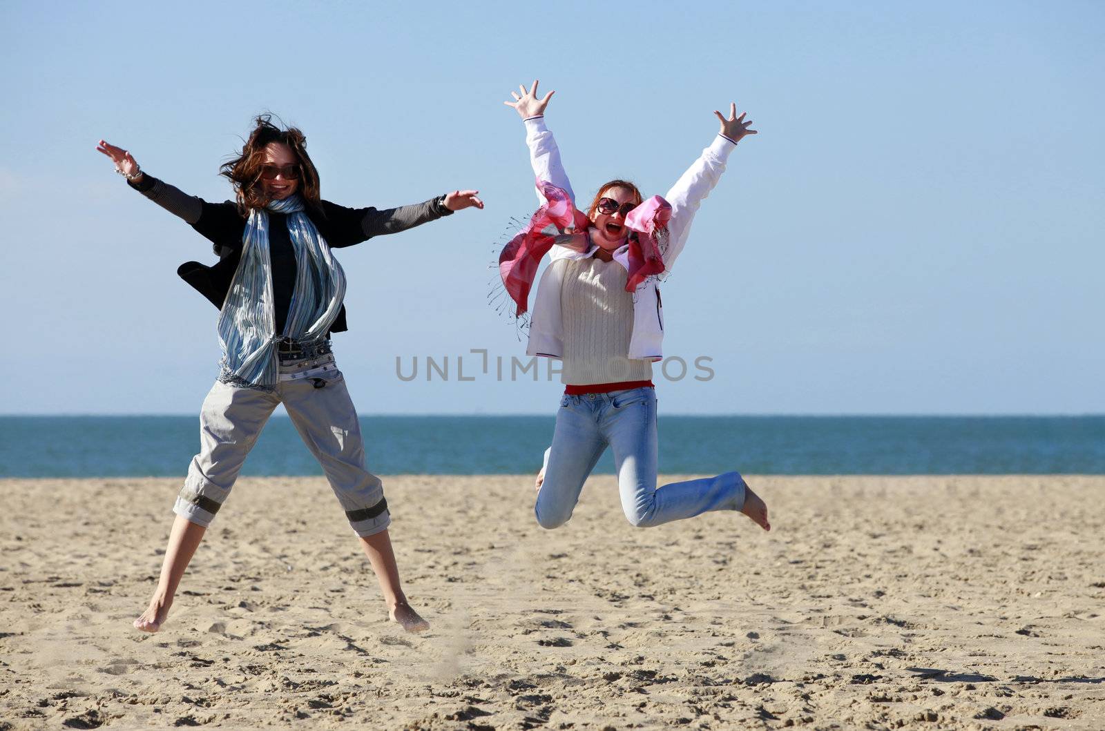 Two happy jumpers girl on the beach 