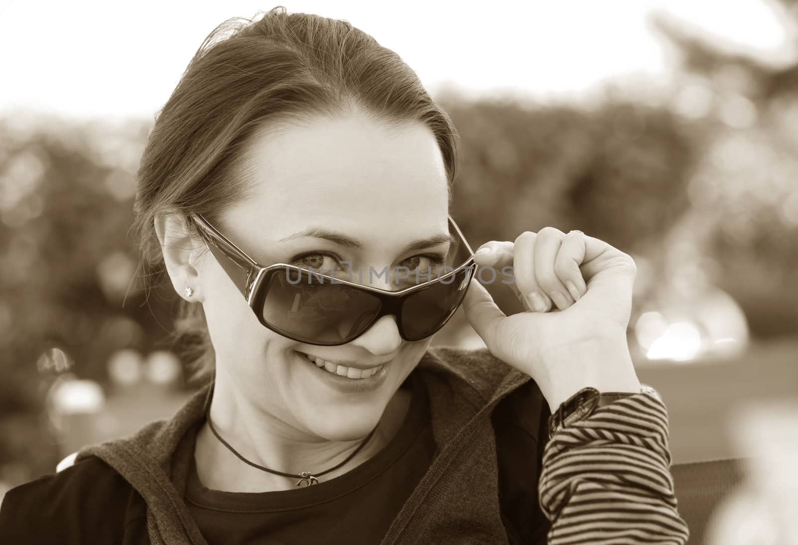 Beautiful smiling woman wearing sunglasses. Sepia