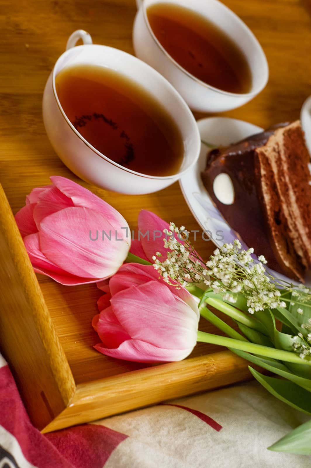 Breakfast tray on bed with tea, cakes and tulips