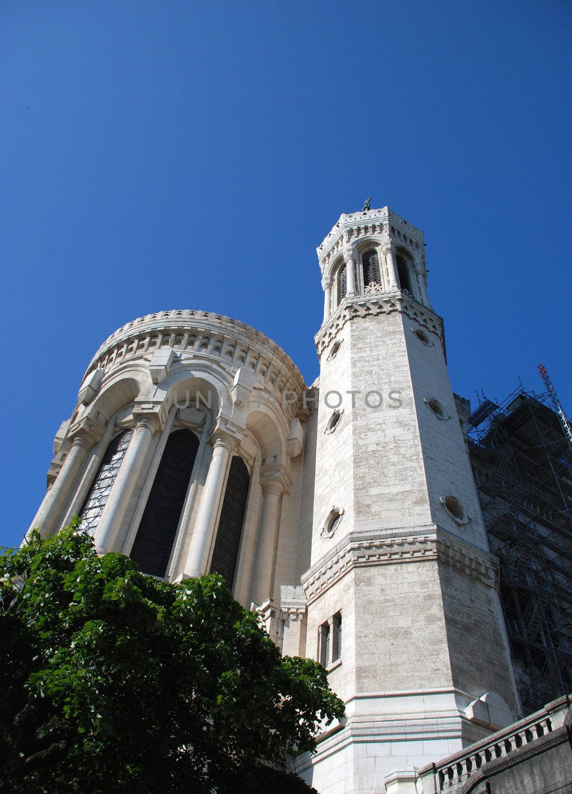 We can see this Basilic situated in Lyon, a big town in France, from the bottom . It is white,  old religious construction , with very specific detailes, wihth a baroque style.It forms part of the lyon's patrimony. In the background there is the blue sky.