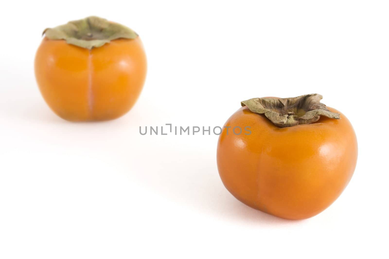 Two persimmons (sharon fruit) isolated on white background.  Fruit in foreground has clipping path