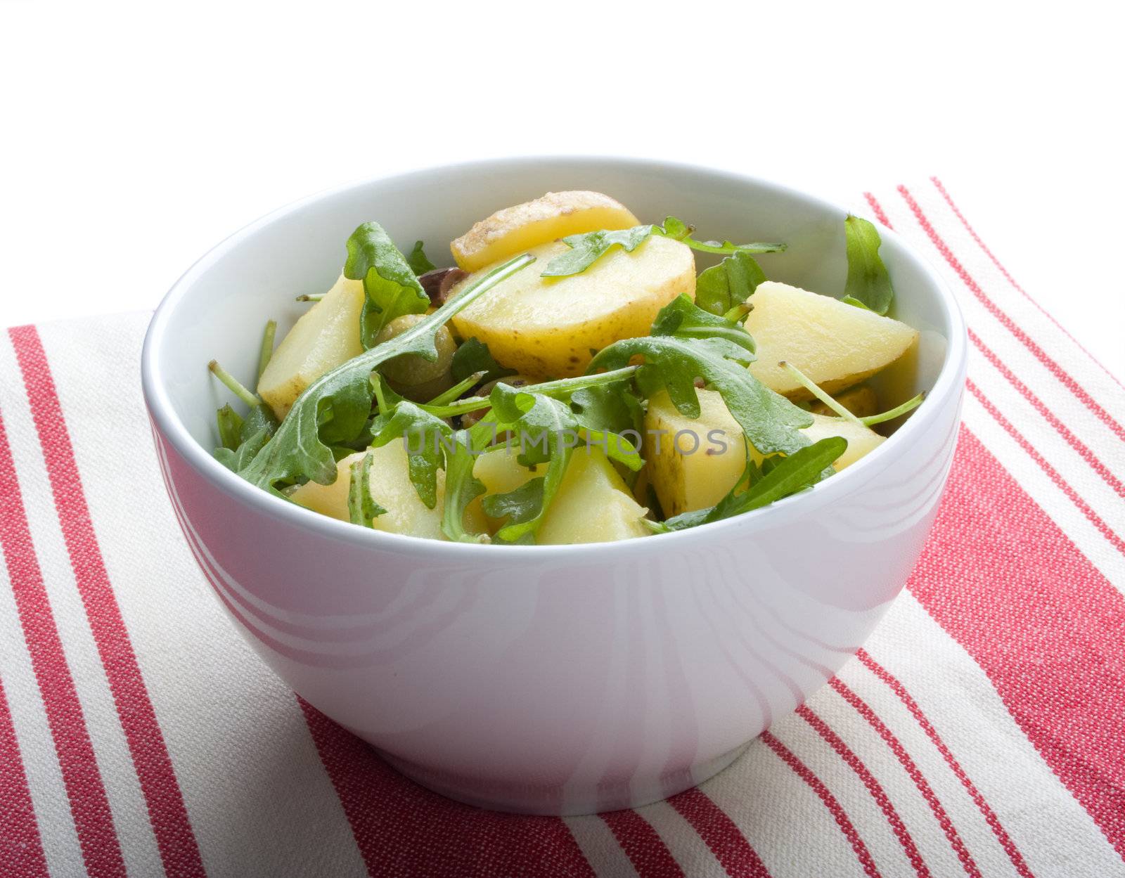 Gourmet potato salad with rocket lettuce, on red and white tablecloth