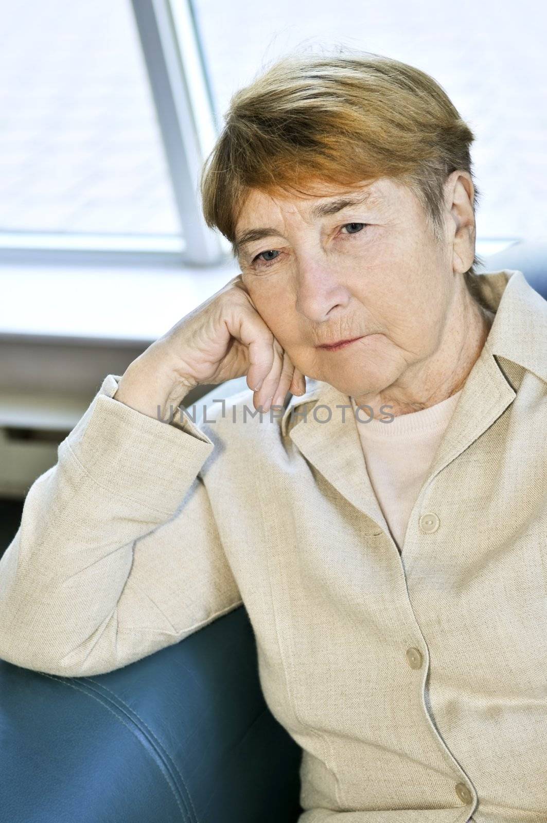 Sad elderly woman sitting on a couch indoors