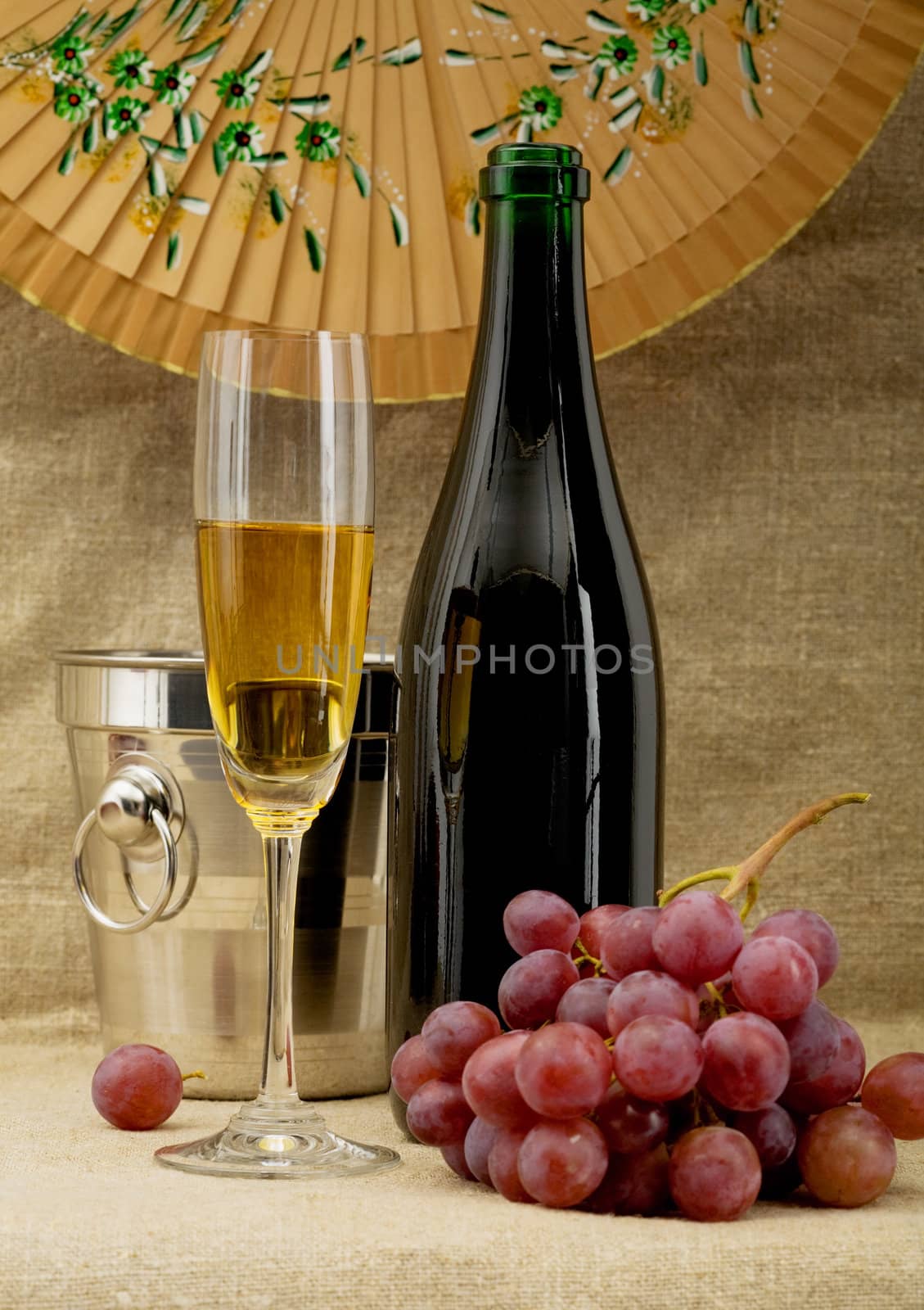 Still life with champagne bottle, bucket, goblet and grapes