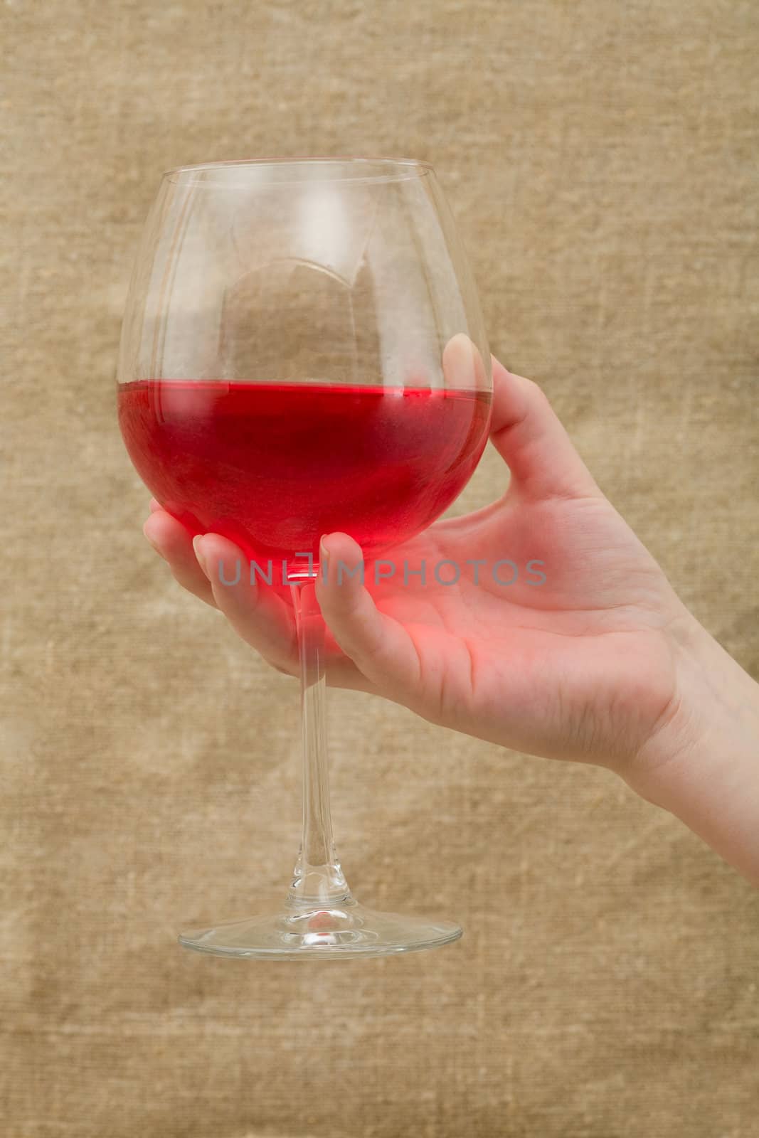 Wineglass of wine on female hand canvas background