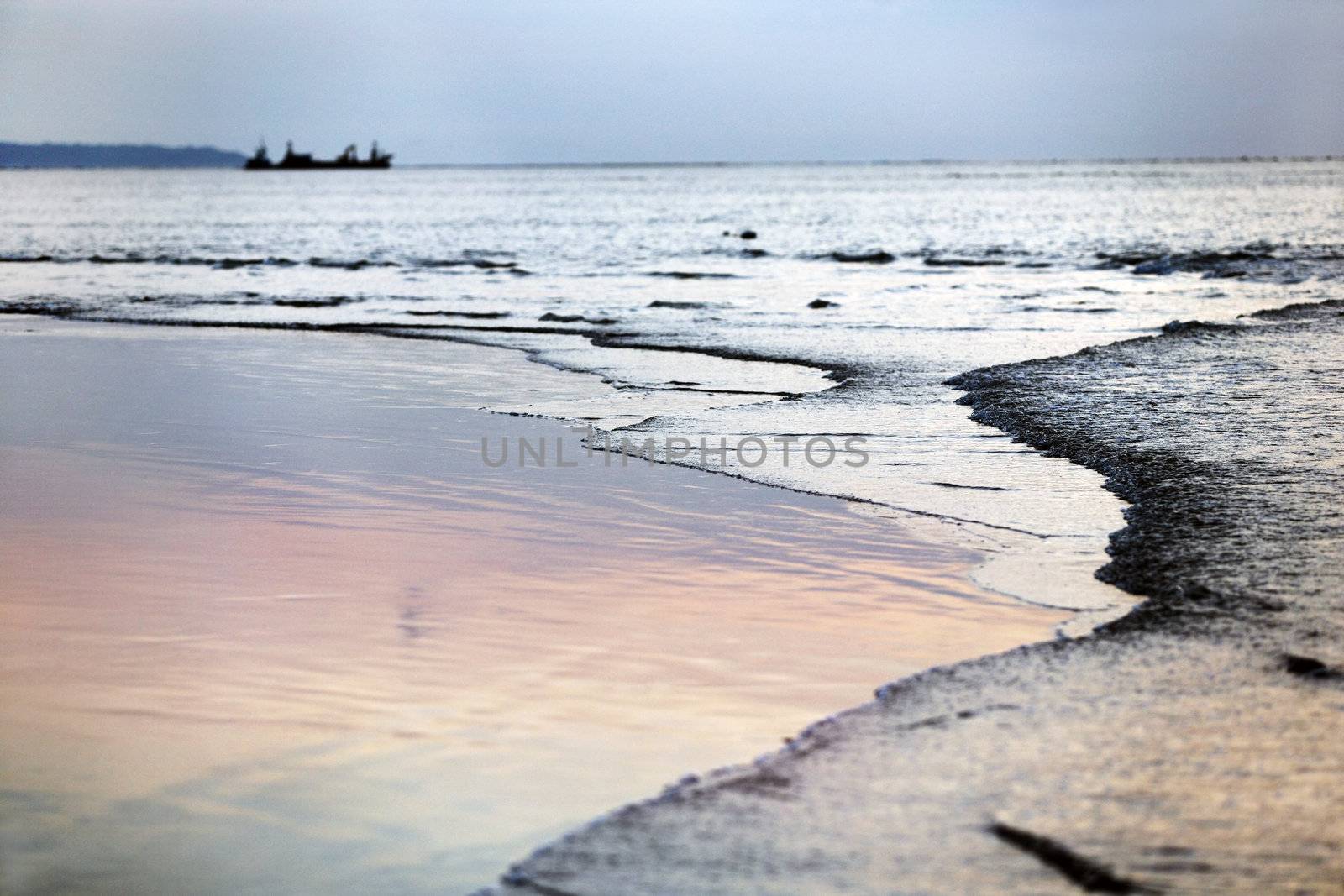 Beach in the winter period, on a background a vessel