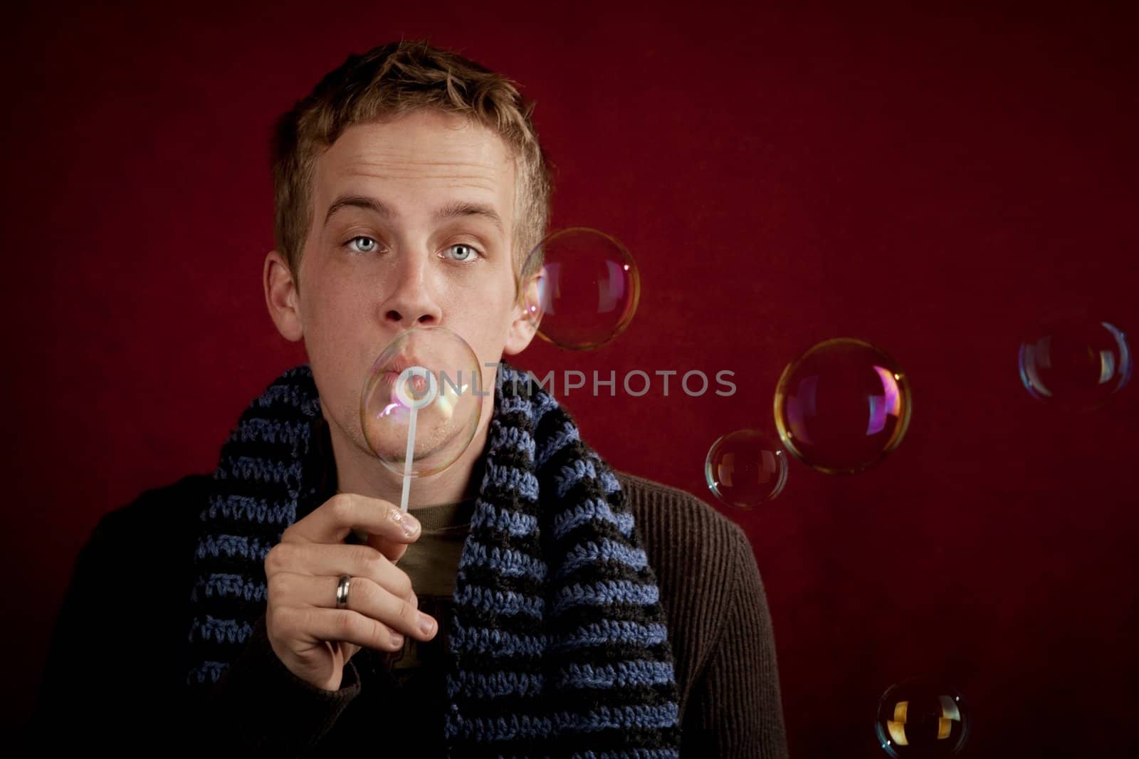 Handsome young blonde man blowing a bubbles