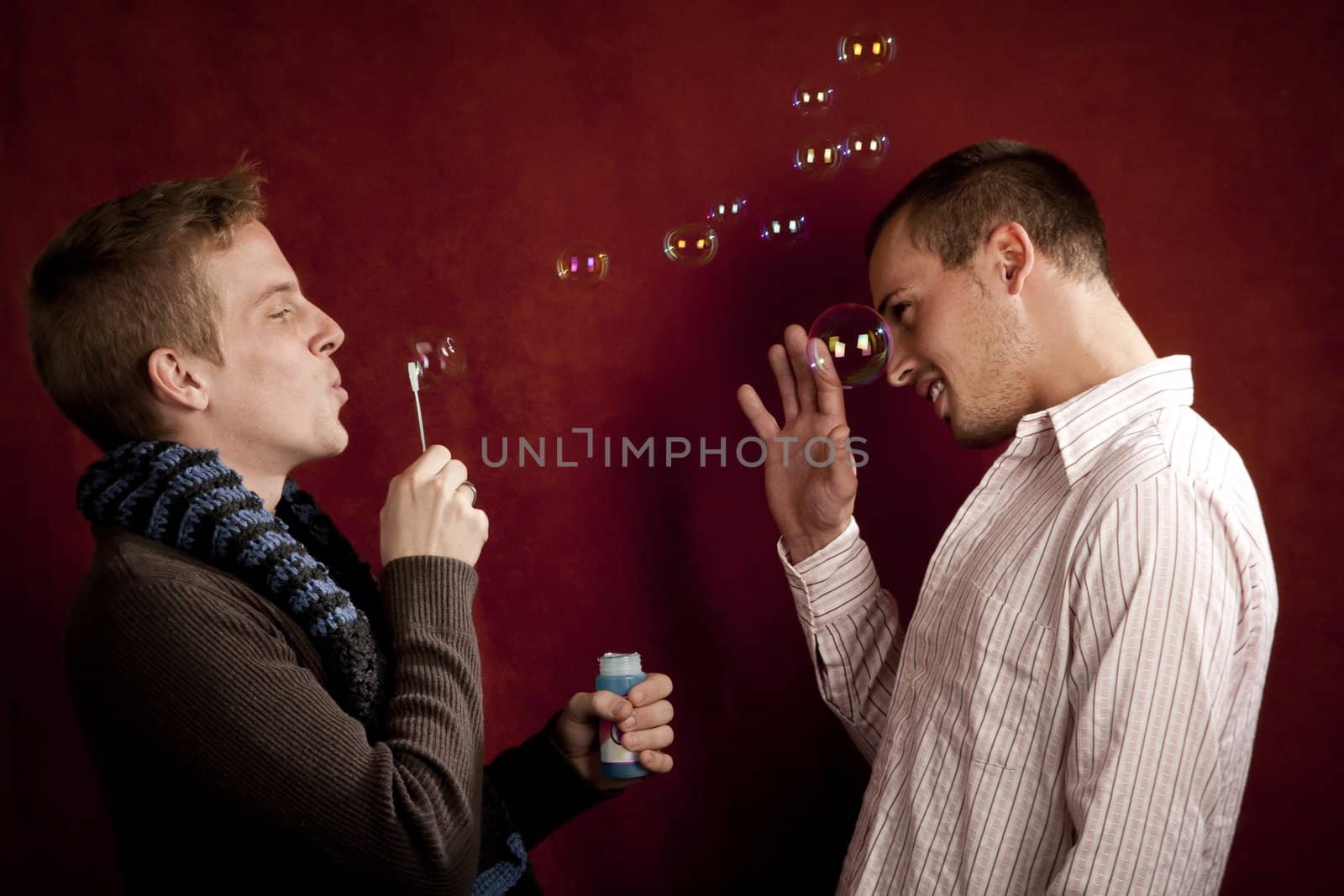 Handsome young blonde man blowing a bubbles at friends