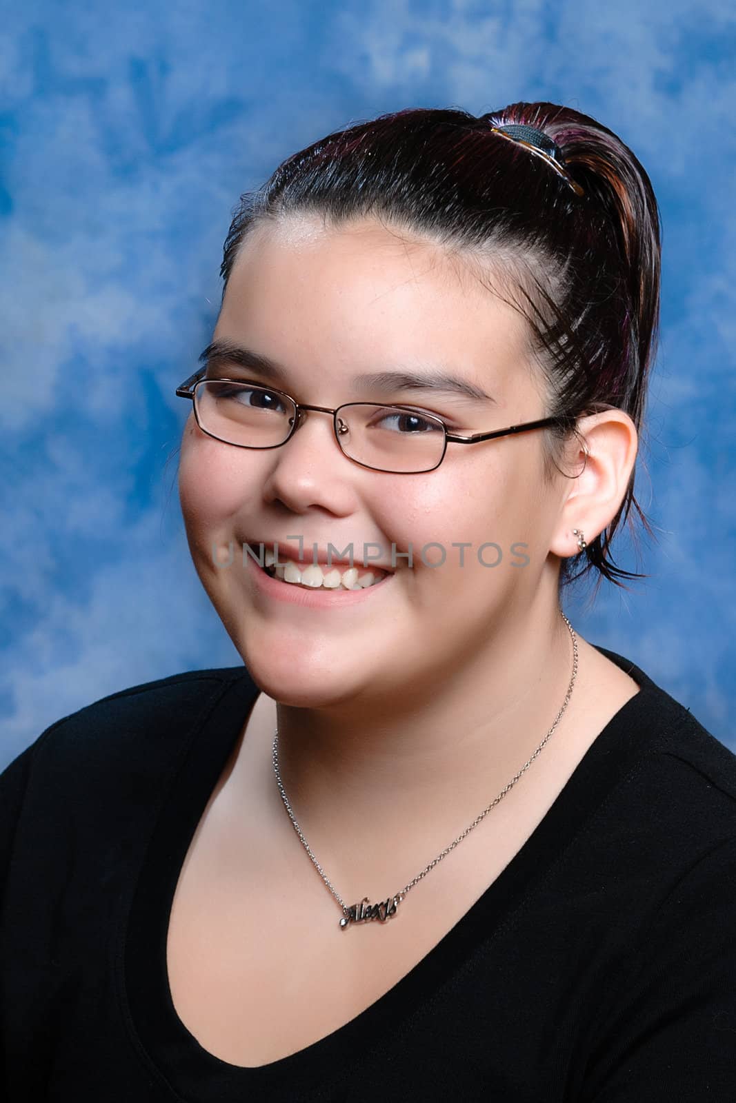 A smiling preteen girl portrait with a blue background