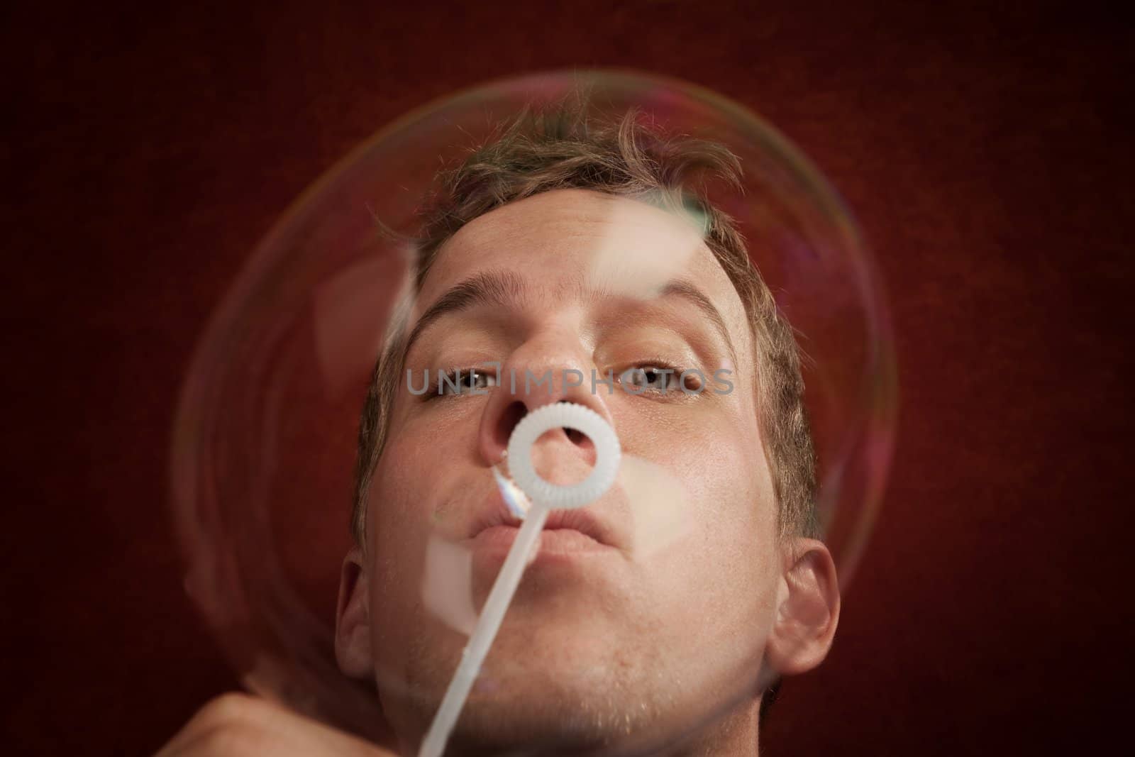 Handsome young blonde man blowing a bubble