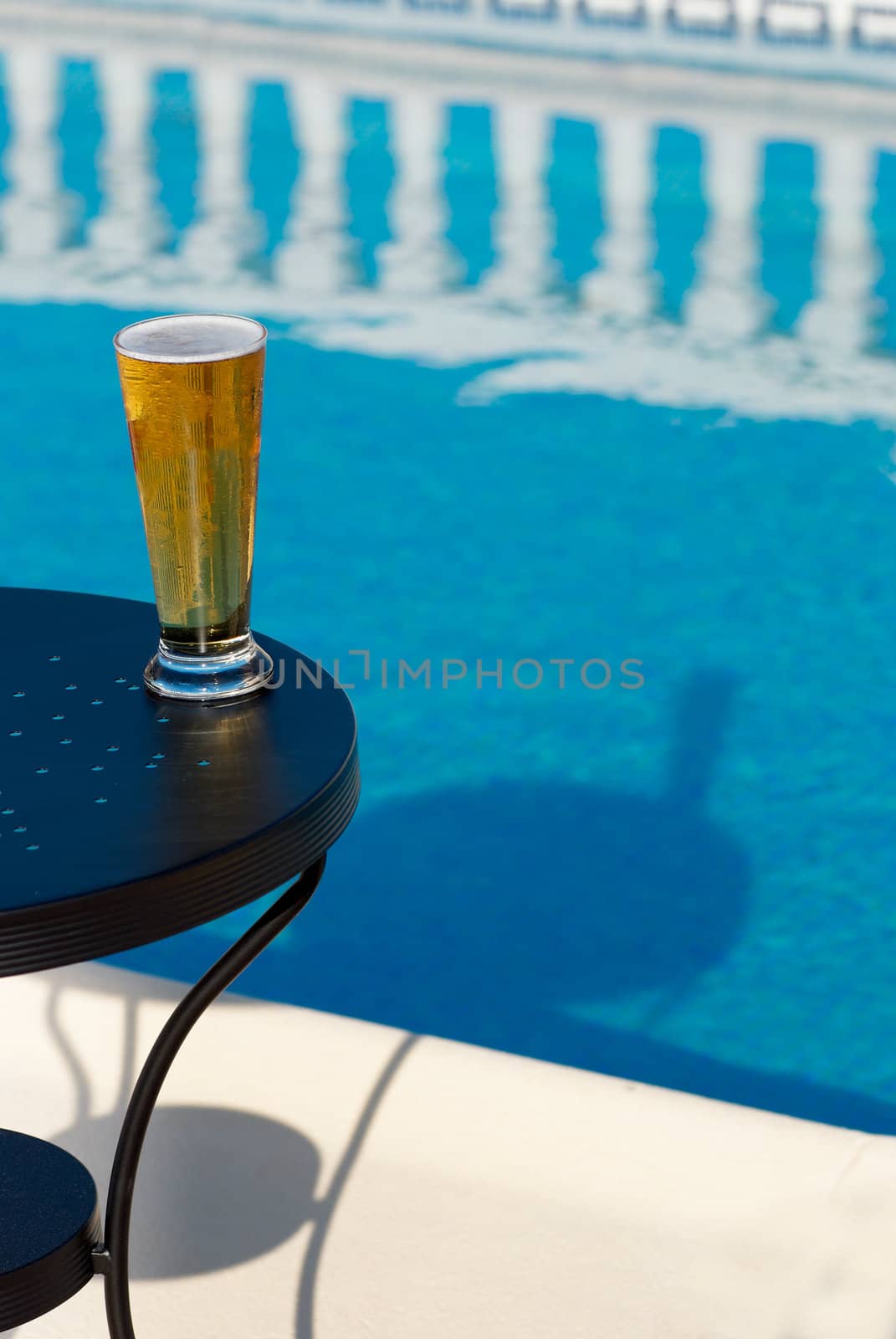 Chilled beer on a table next to a swimming pool