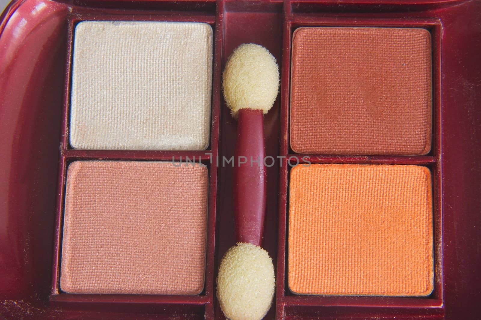 blocks of eye makeup and a makeup brush in a container