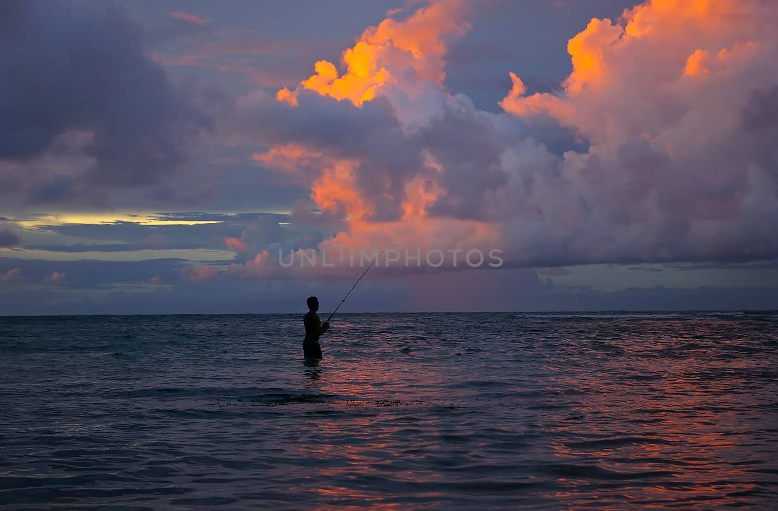 Lone fisherman fishing in the Indian Ocean, Padang beach, Bali, Indonesia.