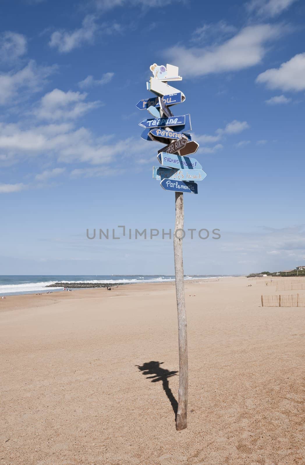 Lot of signs in only one roadsign to the world surf spots on a beach with a blue sky